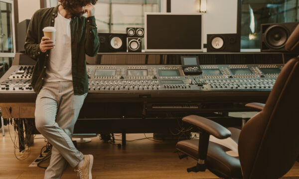young sound producer standing at studio with cup of coffee to go young sound producer standing at studio with cup of coffee to go