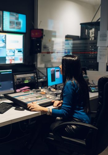 Beautiful middle aged beautiful woman working on a tv station as a producer in a broadcast control room. Show production maker. Television.